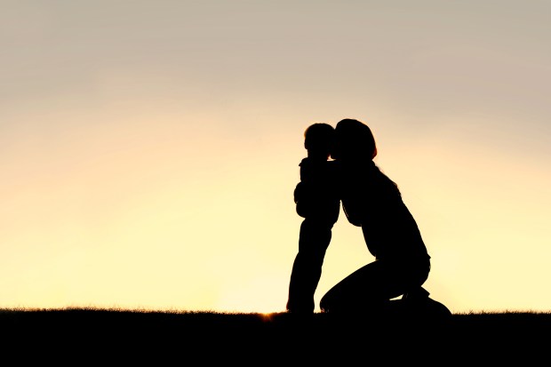 Silhouette of Young Mother Hugging Toddler Son at Sunset
